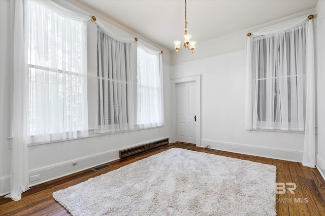 empty room with a chandelier, dark wood-type flooring, and visible vents