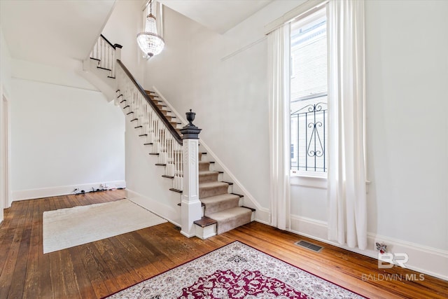 entryway with stairway, hardwood / wood-style flooring, baseboards, and visible vents