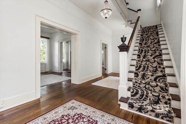 entryway featuring stairway, an inviting chandelier, baseboards, and wood finished floors
