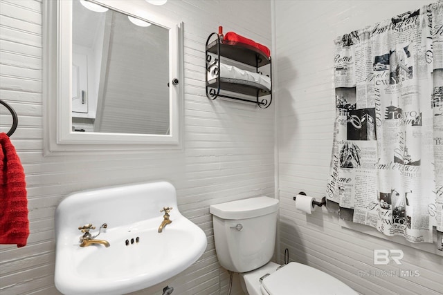 bathroom featuring toilet and tile walls