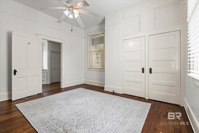 unfurnished bedroom featuring baseboards, ceiling fan, and dark wood-type flooring