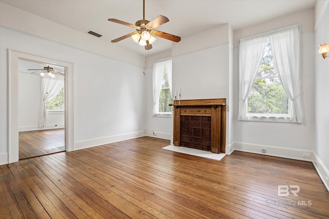 unfurnished living room with baseboards, visible vents, ceiling fan, and hardwood / wood-style flooring