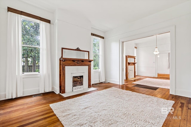 living room with baseboards, a fireplace with flush hearth, hardwood / wood-style floors, and visible vents