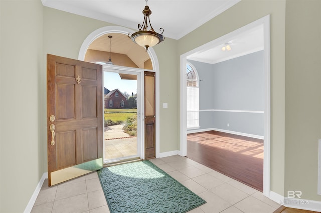 entrance foyer with light tile patterned floors, ceiling fan, and crown molding