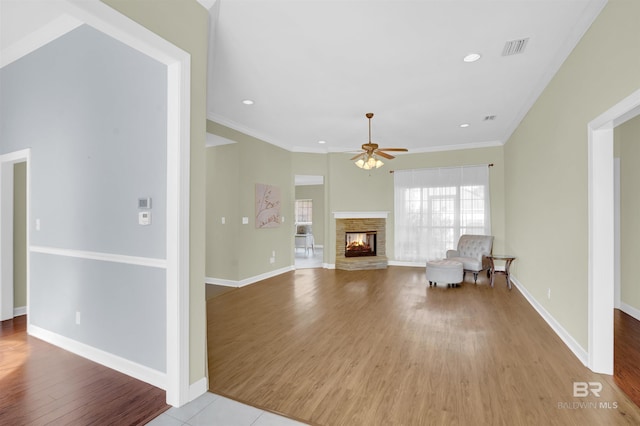 unfurnished living room with ceiling fan, crown molding, light wood-type flooring, and a fireplace