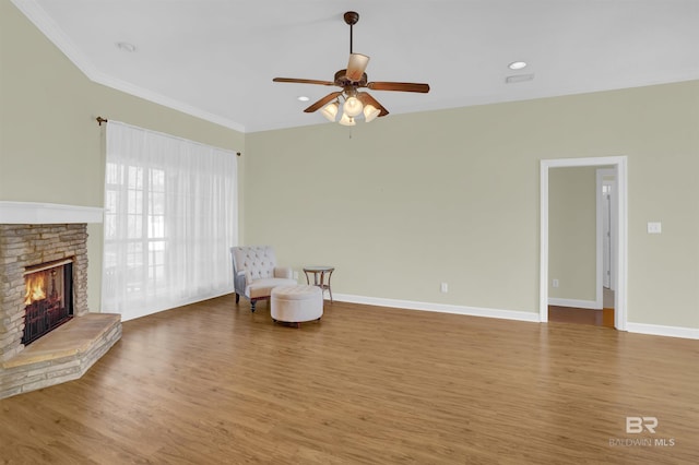 living area featuring ceiling fan, a fireplace, wood-type flooring, and ornamental molding