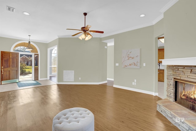 living room featuring a stone fireplace, ceiling fan, hardwood / wood-style floors, and ornamental molding