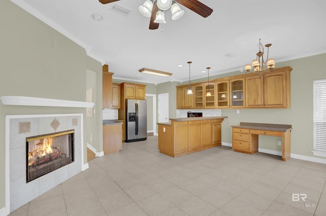 kitchen with a tile fireplace, hanging light fixtures, stainless steel fridge with ice dispenser, crown molding, and ceiling fan with notable chandelier