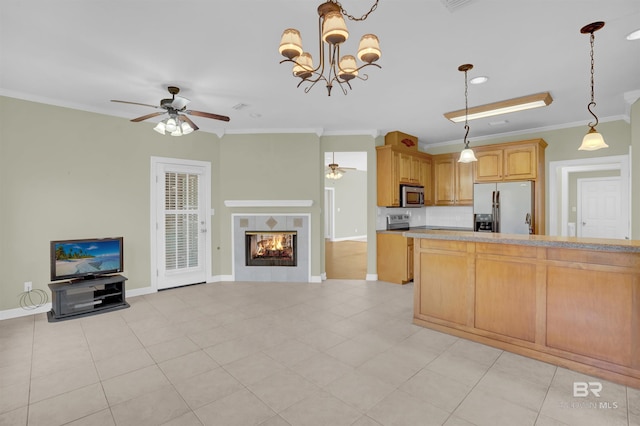 kitchen with a tiled fireplace, pendant lighting, ornamental molding, and appliances with stainless steel finishes