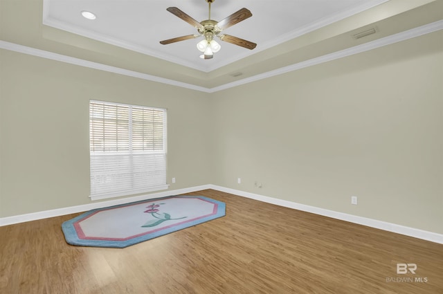 spare room featuring hardwood / wood-style flooring, ceiling fan, ornamental molding, and a tray ceiling