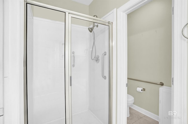 bathroom with tile patterned flooring, toilet, and a shower with shower door