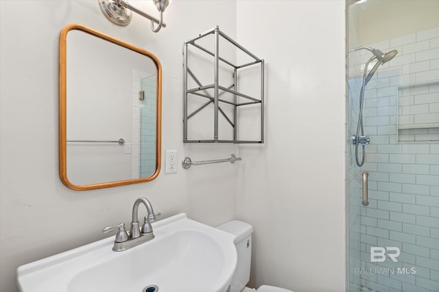 bathroom with toilet, a shower with door, and sink