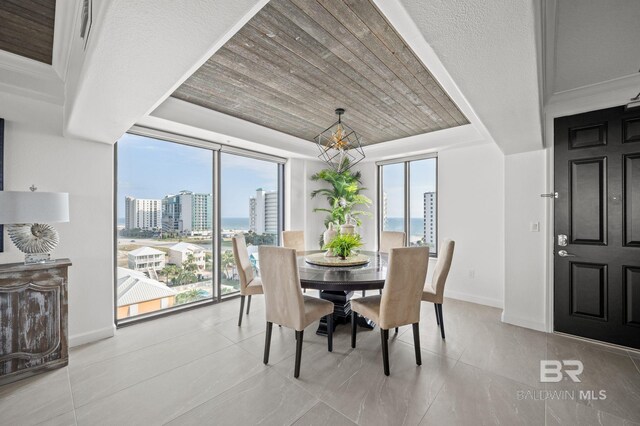29235 Perdido Beach Blvd Unit 703, Orange Beach, AL 36561 - dining room featuring a city view, a chandelier, a tray ceiling, baseboards, and wooden ceiling