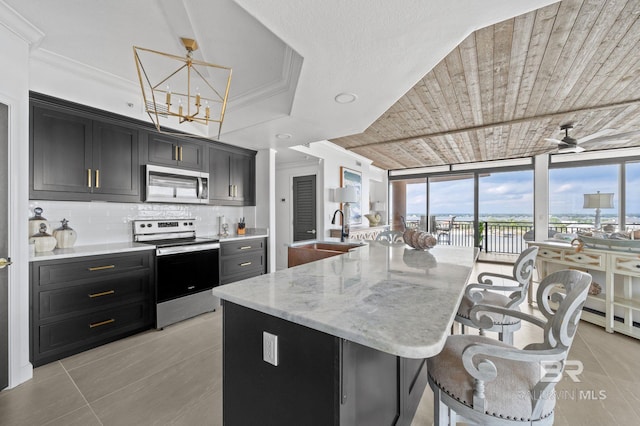 kitchen featuring sink, stainless steel appliances, expansive windows, an island with sink, and a breakfast bar