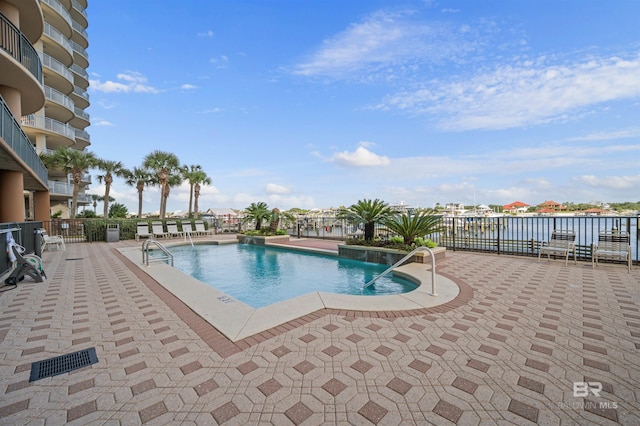 view of pool featuring a water view and a patio