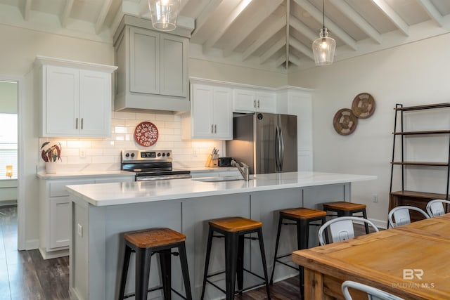 kitchen with stainless steel appliances, a sink, light countertops, decorative backsplash, and beamed ceiling