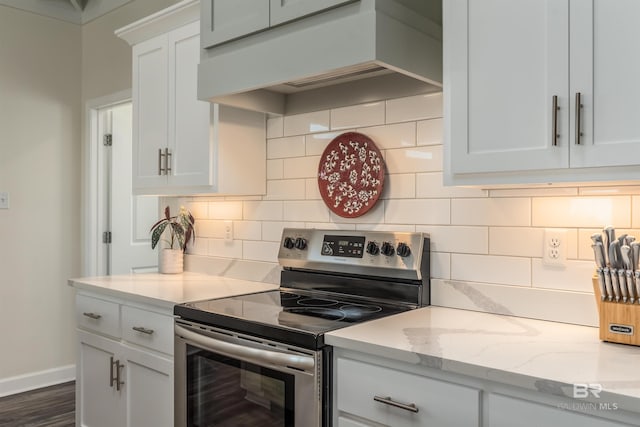 kitchen featuring tasteful backsplash, baseboards, stainless steel range with electric cooktop, premium range hood, and white cabinetry