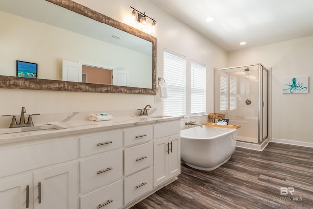 bathroom with a stall shower, a freestanding tub, a sink, and wood finished floors