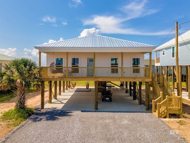 view of front of home featuring metal roof, a carport, gravel driveway, and stairs