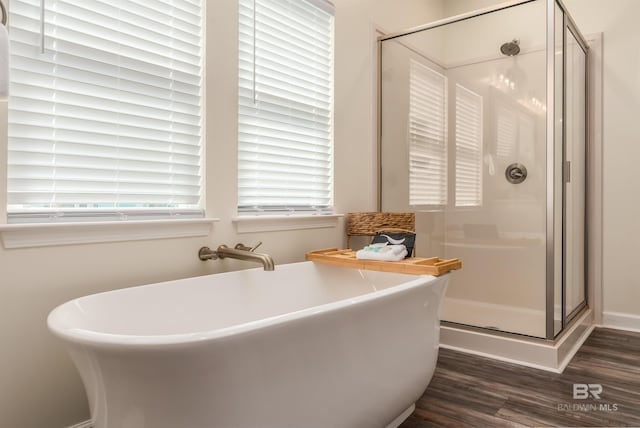 bathroom featuring a freestanding bath, a stall shower, wood finished floors, and a healthy amount of sunlight