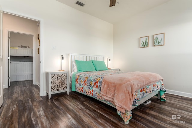 bedroom with a ceiling fan, visible vents, baseboards, and wood finished floors