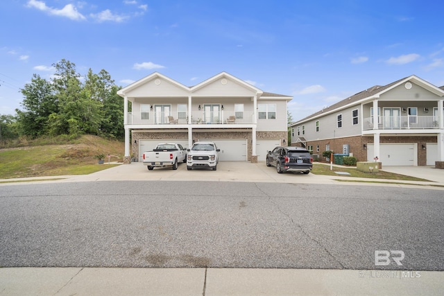 beach home featuring an attached garage, a balcony, and driveway