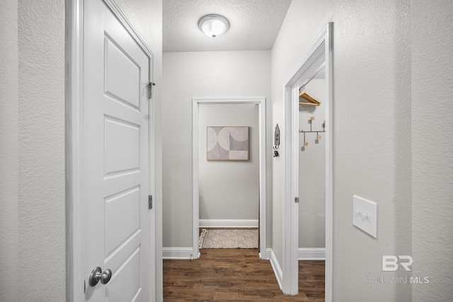 hall featuring baseboards, a textured ceiling, and dark wood-style flooring