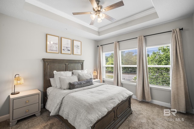 bedroom with carpet floors, ornamental molding, baseboards, and a tray ceiling