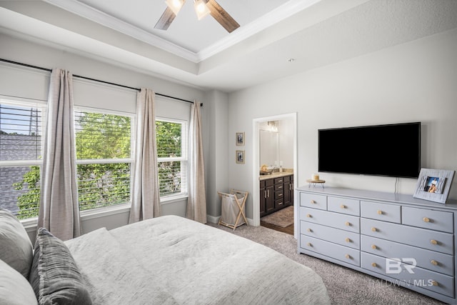 bedroom with crown molding, connected bathroom, carpet floors, a ceiling fan, and a tray ceiling