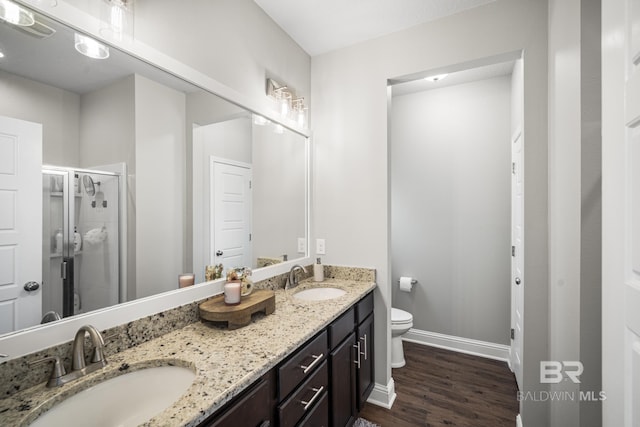 full bathroom featuring a sink, a stall shower, toilet, and wood finished floors