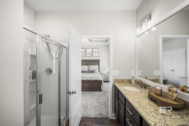ensuite bathroom featuring vanity, ensuite bathroom, a stall shower, and wood finished floors