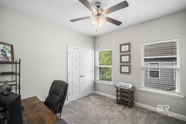 carpeted office space with baseboards and a ceiling fan