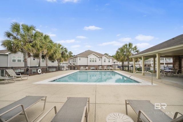 pool with a patio area, fence, and a residential view