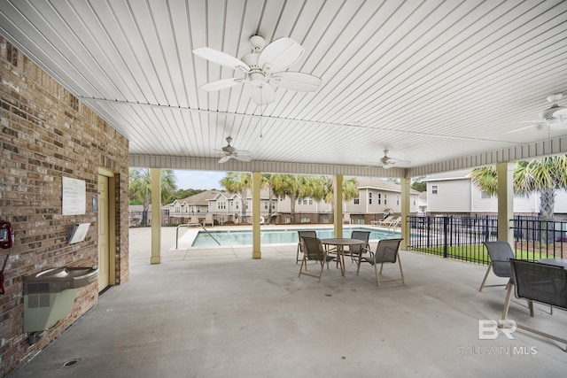view of patio / terrace featuring a ceiling fan, a community pool, and fence