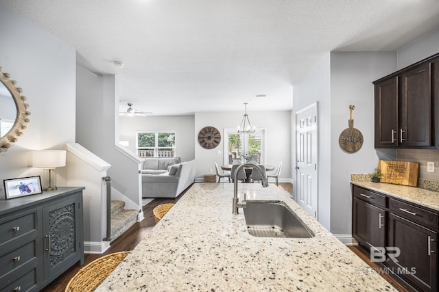 kitchen featuring a sink, light stone countertops, dark brown cabinets, and dark wood-type flooring