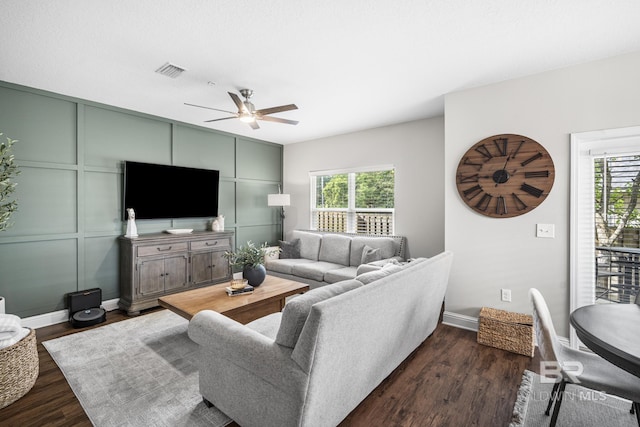 living room with ceiling fan, visible vents, plenty of natural light, and dark wood-type flooring