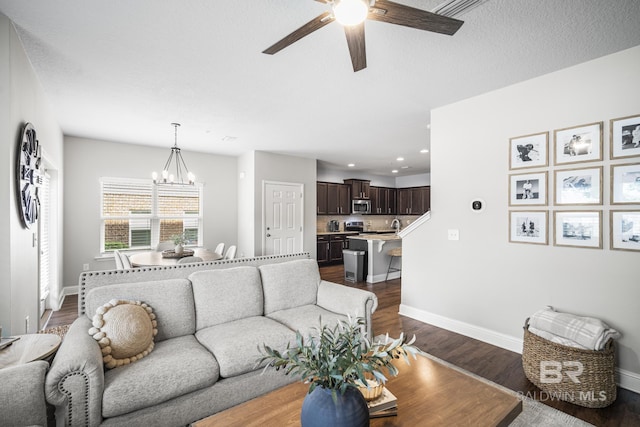 living area with baseboards, recessed lighting, ceiling fan with notable chandelier, and dark wood-style floors