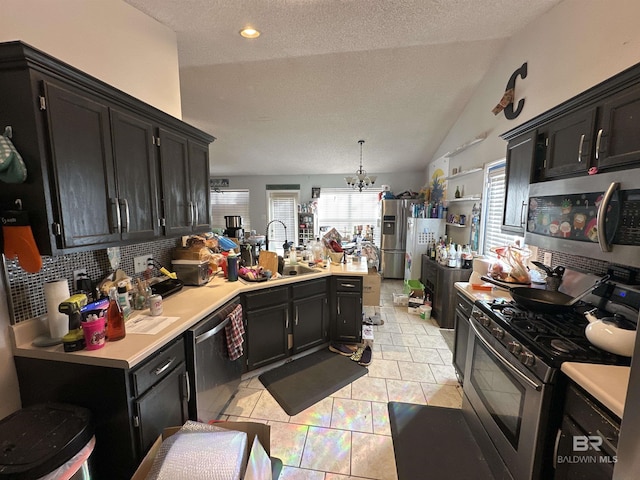 kitchen with appliances with stainless steel finishes, lofted ceiling, plenty of natural light, and sink