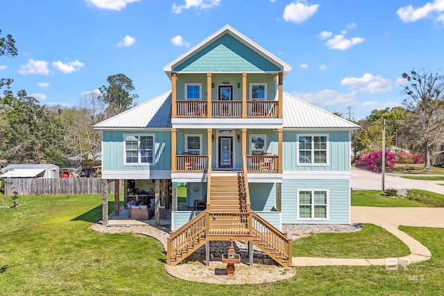 rear view of house with a lawn, covered porch, and a balcony