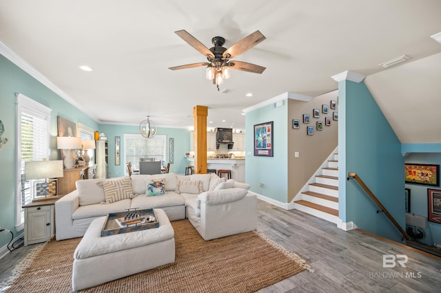 living room featuring ornamental molding, hardwood / wood-style floors, and ceiling fan with notable chandelier