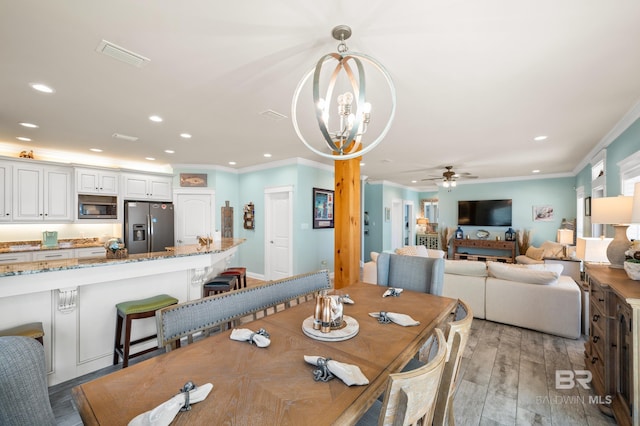 dining area featuring ceiling fan with notable chandelier, light hardwood / wood-style flooring, and crown molding