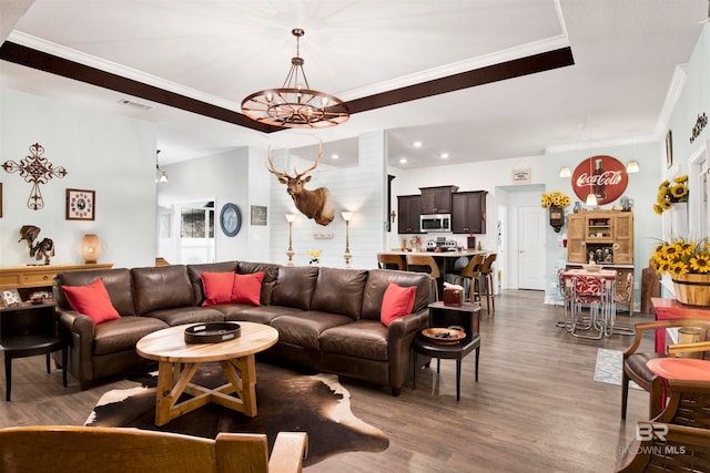 living room with dark wood-type flooring, a chandelier, and crown molding