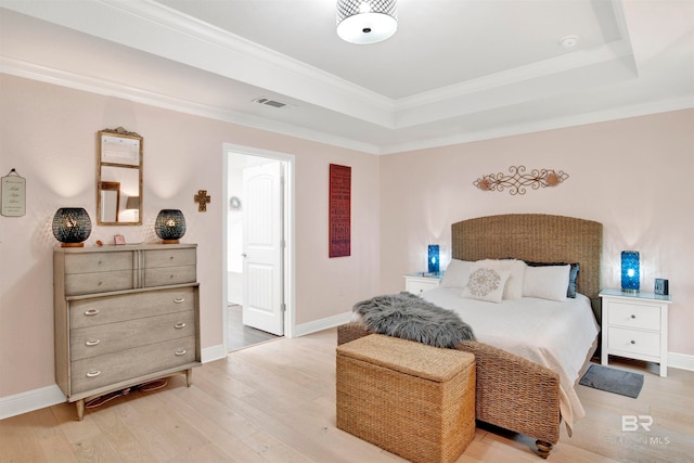 bedroom with light hardwood / wood-style flooring, crown molding, and a tray ceiling