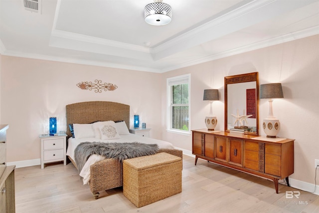 bedroom featuring a tray ceiling, light hardwood / wood-style floors, and crown molding