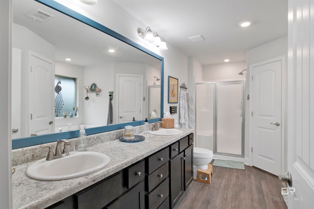 bathroom featuring toilet, vanity, hardwood / wood-style flooring, and a shower with door