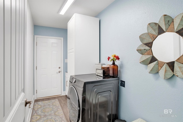 laundry area with light hardwood / wood-style flooring, cabinets, and washer / dryer