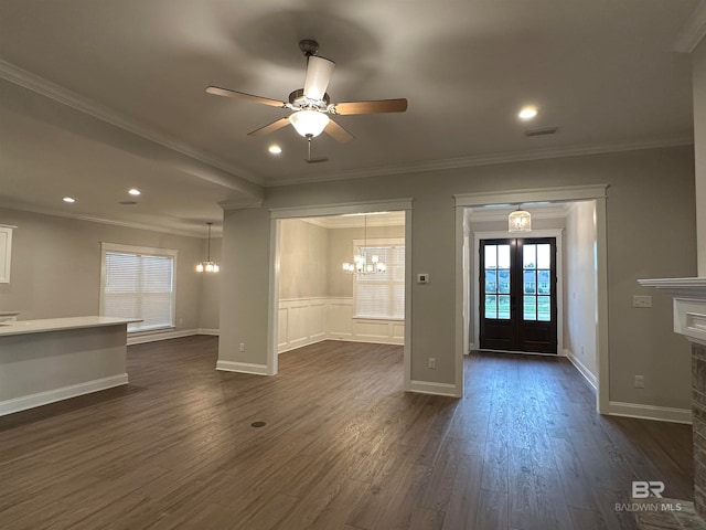 interior space with a stone fireplace, french doors, ceiling fan with notable chandelier, dark hardwood / wood-style floors, and crown molding