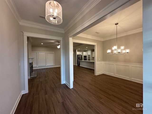 unfurnished dining area featuring dark wood-type flooring, a notable chandelier, ornamental molding, and a fireplace