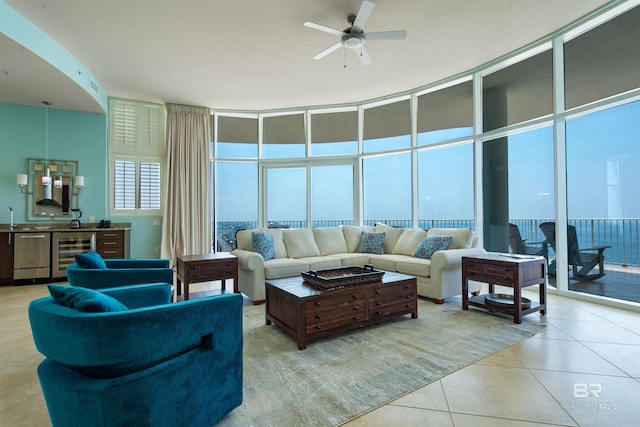 tiled living room with expansive windows, ceiling fan, beverage cooler, and a wood stove