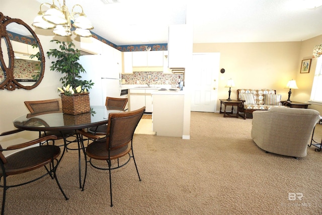 dining space with sink, light carpet, and an inviting chandelier